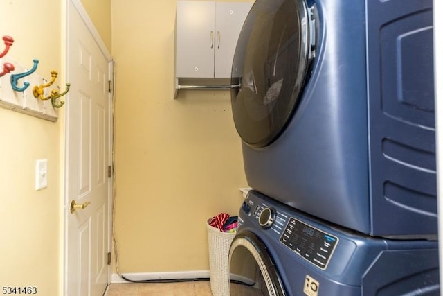 clothes washing area featuring laundry area, stacked washer and dryer, and baseboards