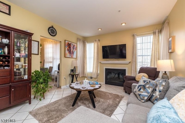 living area with a glass covered fireplace, light tile patterned flooring, and recessed lighting