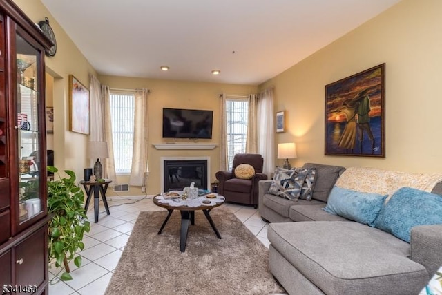 living area featuring a glass covered fireplace and light tile patterned flooring