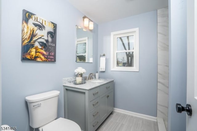 bathroom featuring walk in shower, vanity, toilet, and baseboards