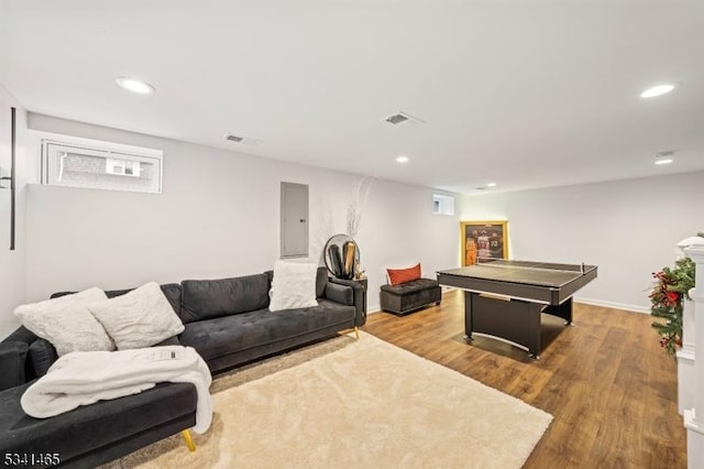 living room with wood finished floors, electric panel, and recessed lighting