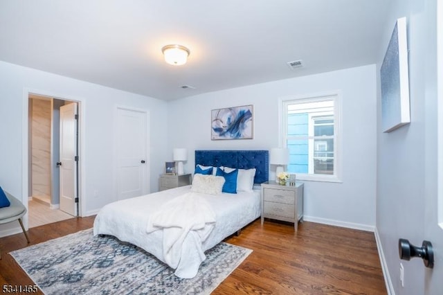 bedroom featuring wood finished floors, visible vents, and baseboards