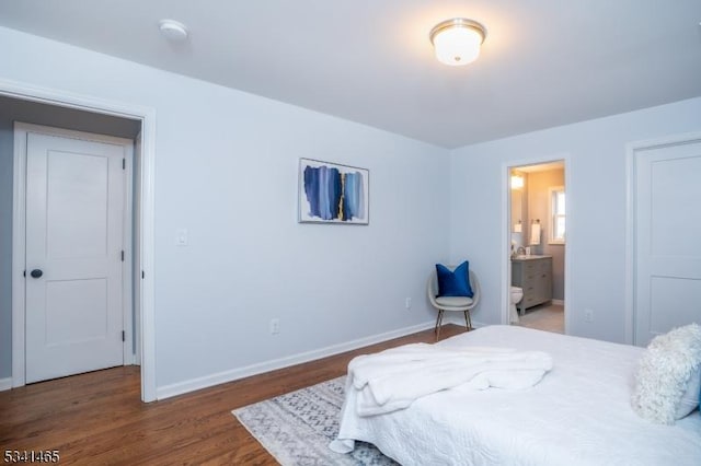 bedroom with ensuite bath, baseboards, and wood finished floors