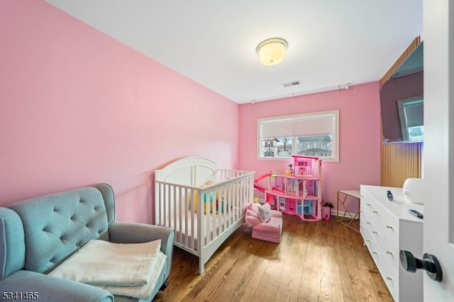 bedroom with visible vents, multiple windows, and wood finished floors