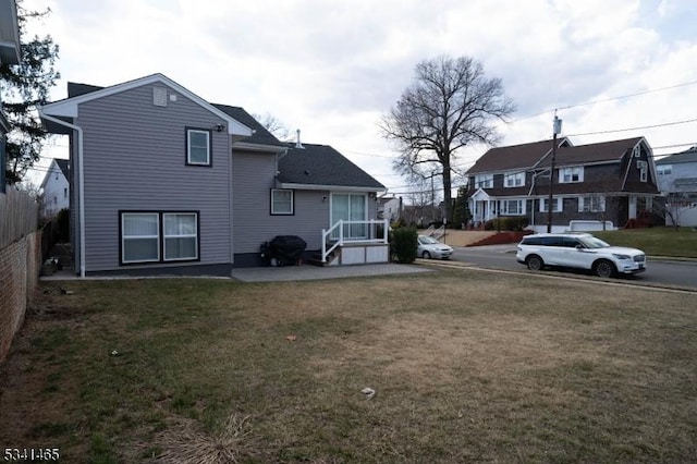 back of house with a patio, a lawn, fence, and a residential view