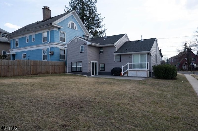 back of house with a chimney, fence, and a yard