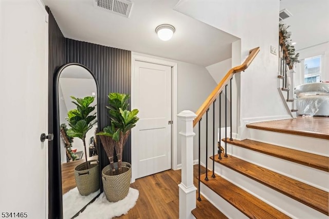 foyer with stairs, visible vents, and wood finished floors