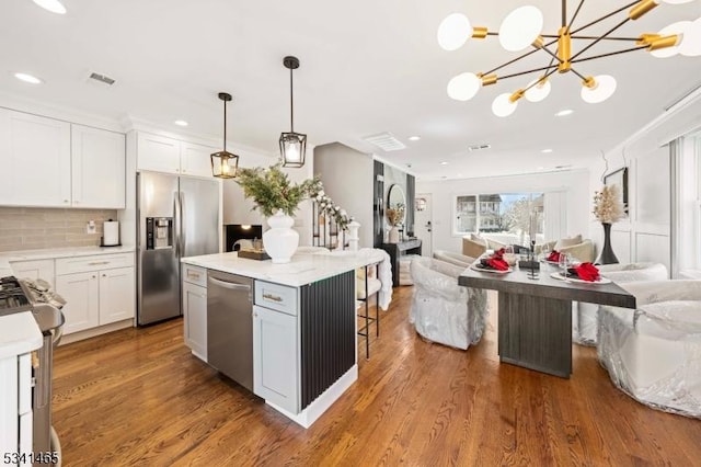 kitchen featuring visible vents, appliances with stainless steel finishes, open floor plan, and wood finished floors