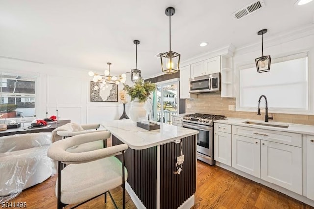 kitchen with stainless steel appliances, tasteful backsplash, visible vents, white cabinetry, and a sink