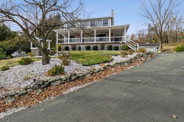 view of front of property featuring covered porch, a chimney, and a detached garage