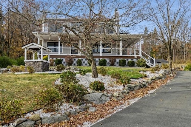 farmhouse-style home with stairway and a front lawn