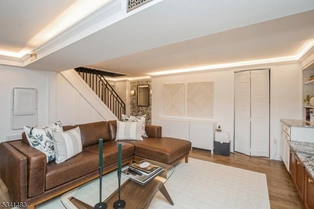 living area featuring stairs, ornamental molding, and light wood-type flooring