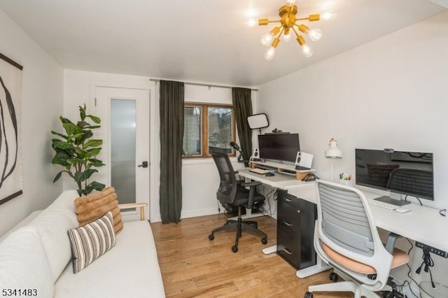 home office featuring light wood-type flooring and a notable chandelier