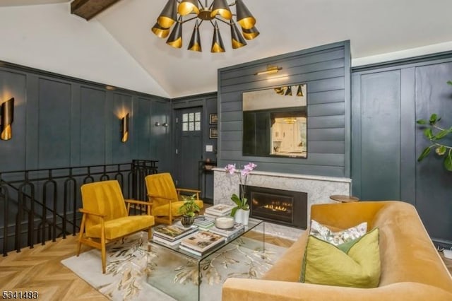 living area with lofted ceiling with beams, an inviting chandelier, a decorative wall, and a high end fireplace