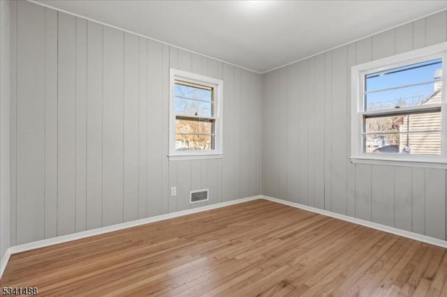 empty room with baseboards, plenty of natural light, and light wood finished floors