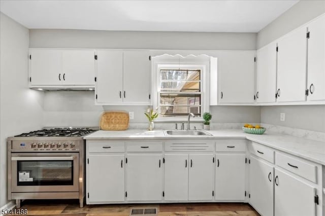 kitchen with stainless steel gas range oven, visible vents, white cabinets, light countertops, and under cabinet range hood