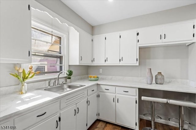 kitchen featuring dark wood-type flooring, white cabinets, a sink, and light countertops