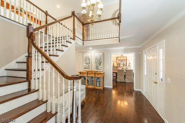 foyer entrance with a chandelier, wood finished floors, baseboards, stairway, and crown molding