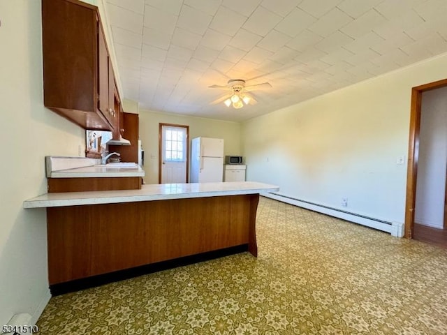 kitchen with a baseboard radiator, freestanding refrigerator, light countertops, and a peninsula