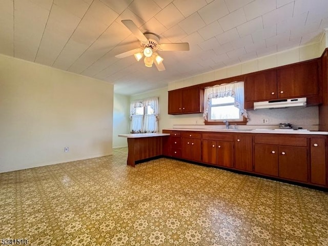 kitchen featuring light floors, under cabinet range hood, light countertops, and a sink