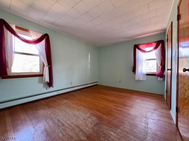 unfurnished bedroom with wood-type flooring and a baseboard heating unit