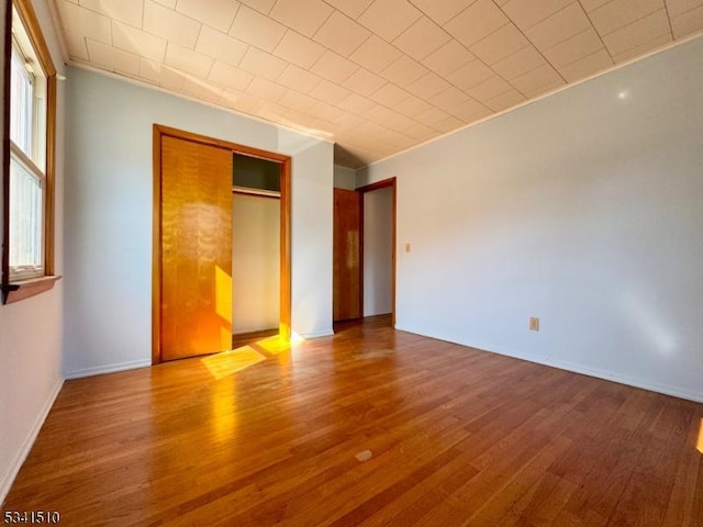 unfurnished bedroom featuring a closet, baseboards, and wood finished floors