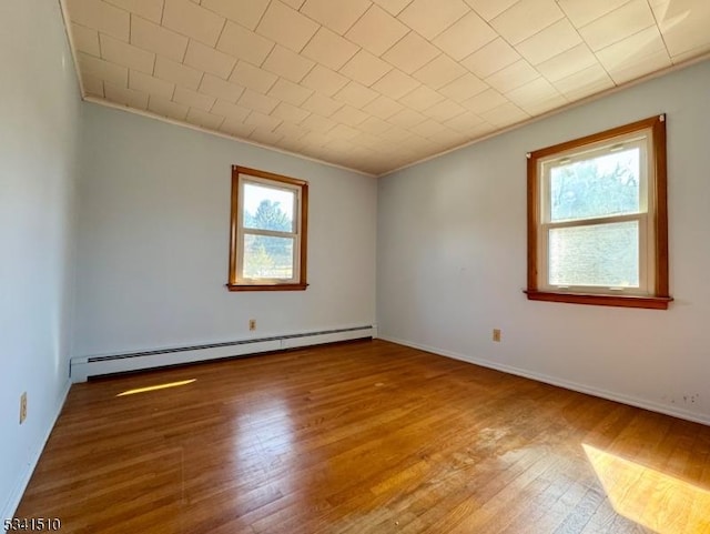 spare room with baseboards, a baseboard radiator, ornamental molding, and wood finished floors