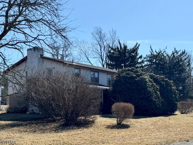 view of home's exterior featuring a lawn and a chimney