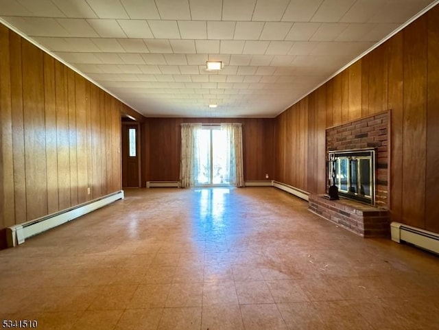 unfurnished living room with a baseboard heating unit, wood walls, and a brick fireplace