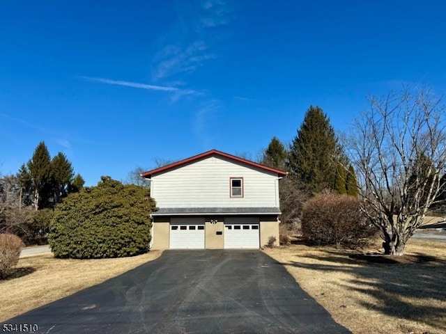 view of home's exterior with a garage, aphalt driveway, and stucco siding