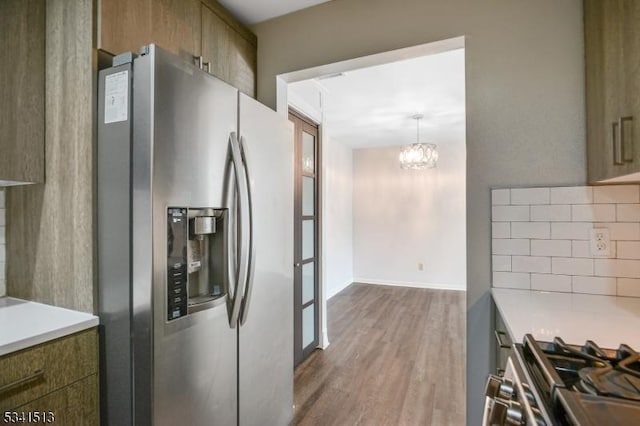 kitchen with brown cabinetry, wood finished floors, stainless steel appliances, decorative backsplash, and light countertops