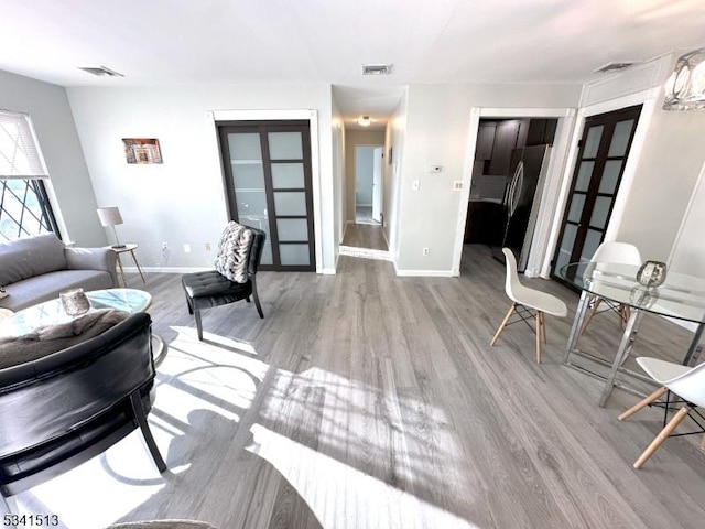 living room featuring french doors, baseboards, visible vents, and wood finished floors