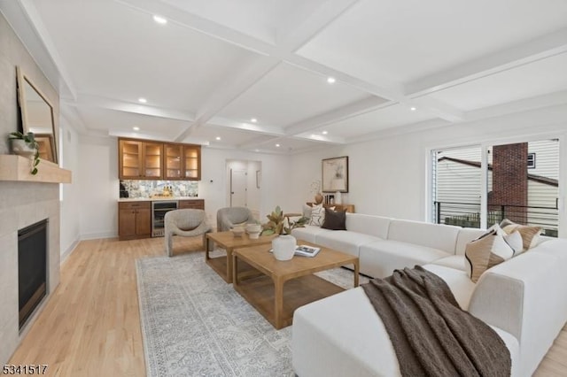 living area featuring beamed ceiling, light wood-style flooring, coffered ceiling, recessed lighting, and indoor wet bar