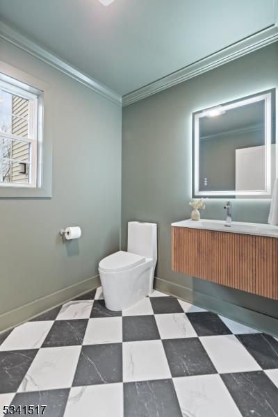 bathroom with vanity, toilet, crown molding, and baseboards