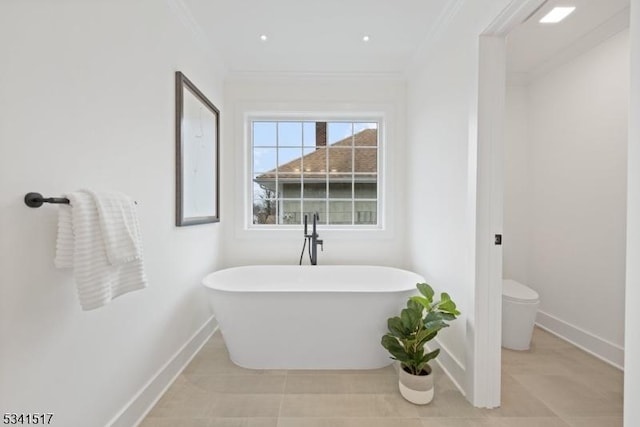 bathroom with a freestanding tub, toilet, baseboards, and ornamental molding