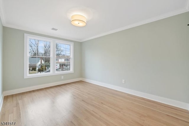 spare room featuring baseboards, light wood-style floors, and ornamental molding