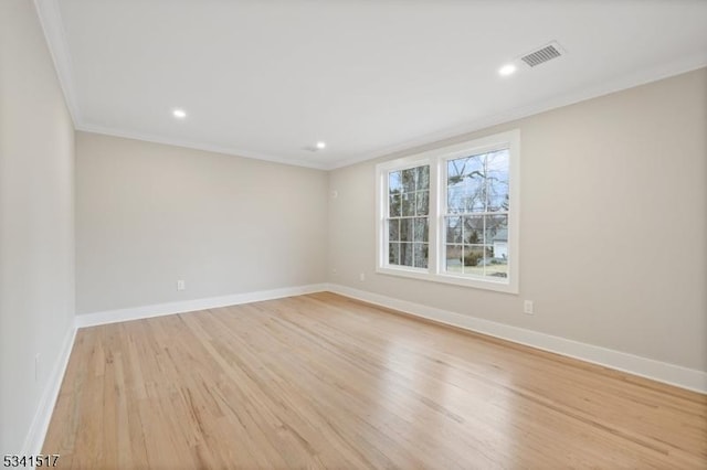 unfurnished room with visible vents, light wood-style flooring, baseboards, and ornamental molding