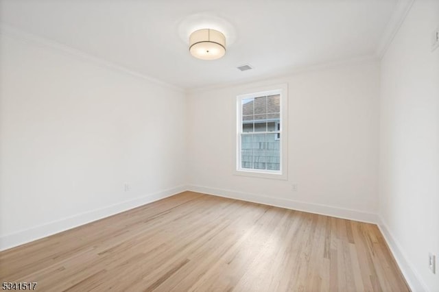 spare room featuring light wood finished floors, visible vents, baseboards, and ornamental molding