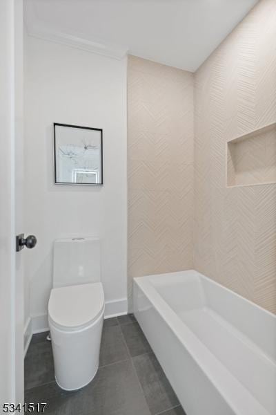 bathroom with toilet, tile patterned floors, a bath, and baseboards