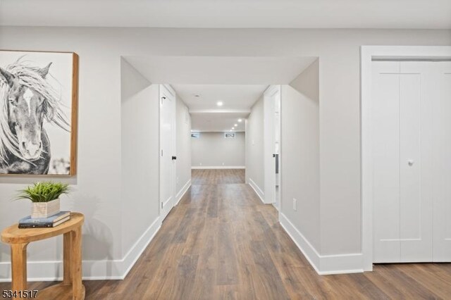 corridor with recessed lighting, wood finished floors, and baseboards