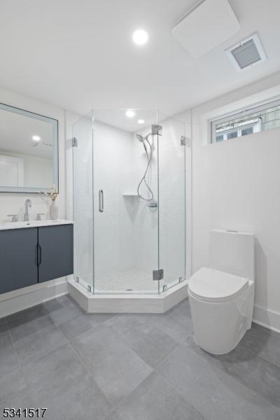 bathroom featuring vanity, toilet, visible vents, and a stall shower