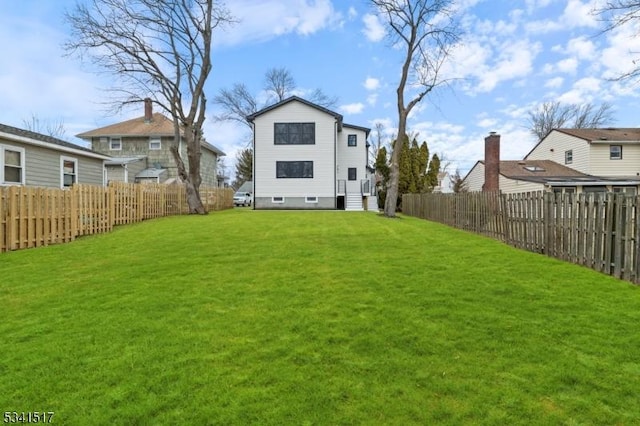 rear view of property featuring a yard and a fenced backyard