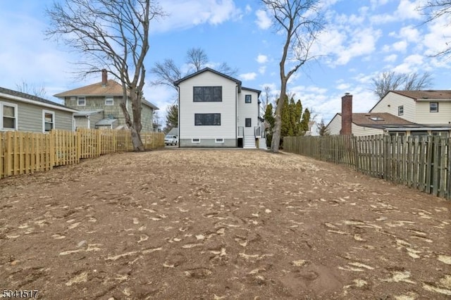 rear view of house featuring a fenced backyard