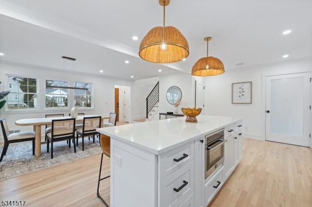 kitchen with a kitchen bar, recessed lighting, white cabinetry, and oven