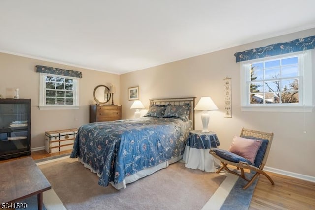 bedroom featuring multiple windows, baseboards, and wood finished floors