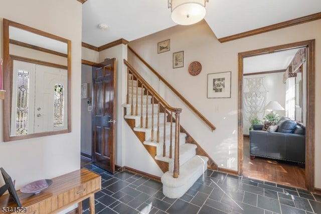 foyer entrance featuring baseboards, stairway, and crown molding