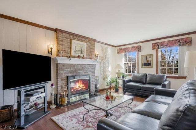 living room with ornamental molding, plenty of natural light, wood finished floors, and a brick fireplace