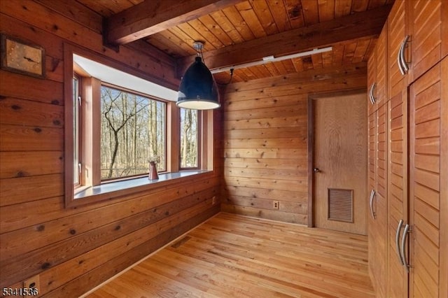 unfurnished room with wood walls, wood ceiling, visible vents, and light wood-style floors