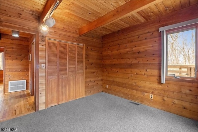 unfurnished bedroom with wood walls, visible vents, and beam ceiling