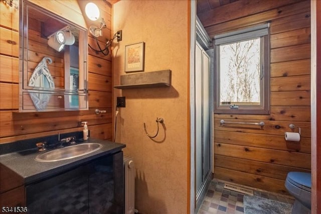 full bath with tile patterned floors, wooden walls, toilet, and vanity